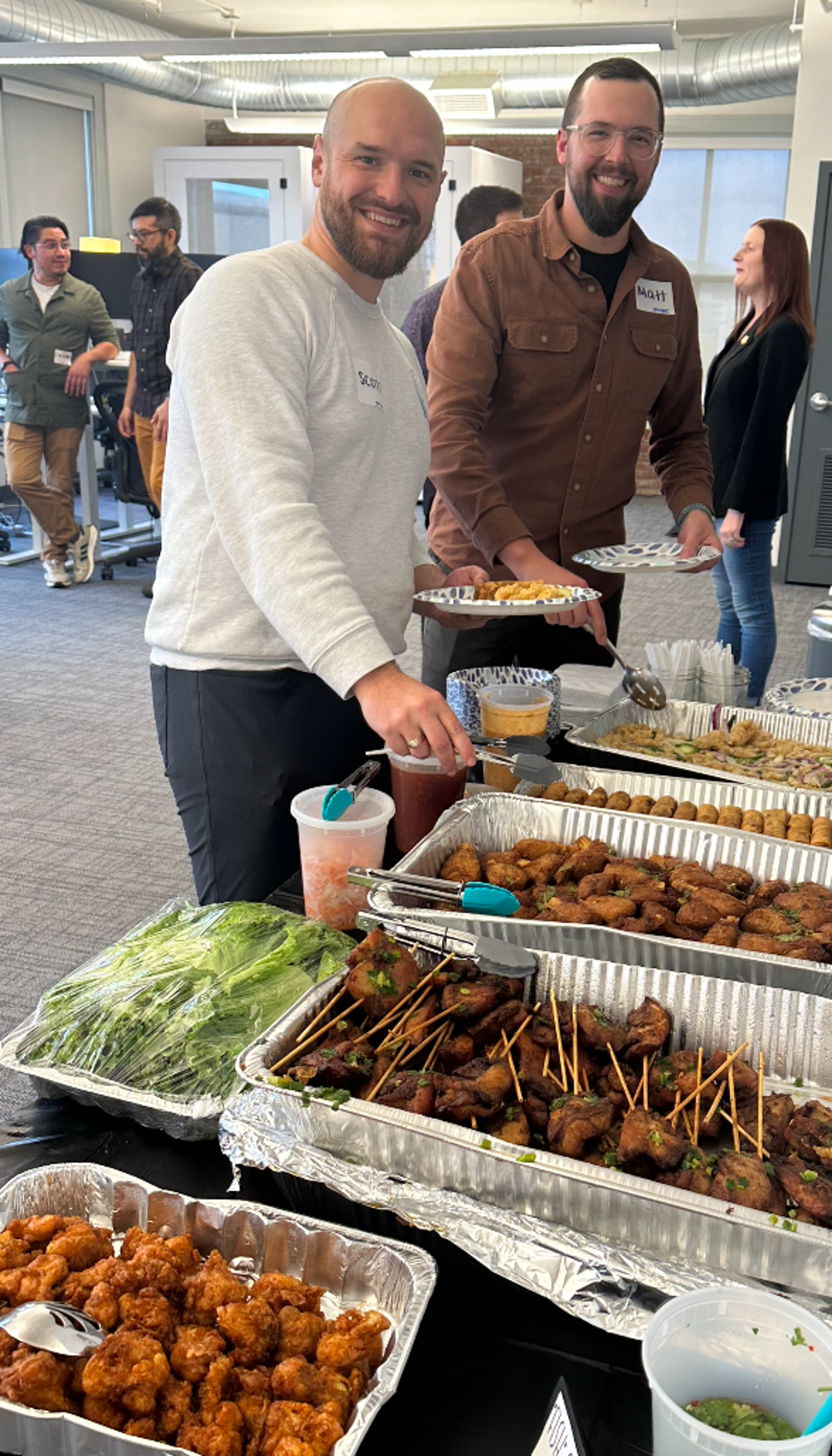 Guests enjoying Friendship Kitchen catering beside a buffet at an office event